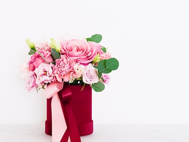 Schöner Strauß blühender Blumen in rotem Blumenkasten auf weißem Hintergrund Urlaubsgeschenk Luxus-Blumenmuster