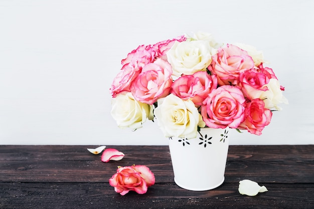 Schöner Strauß der rosa und weißen Rosen in der weißen Vase auf Holztisch