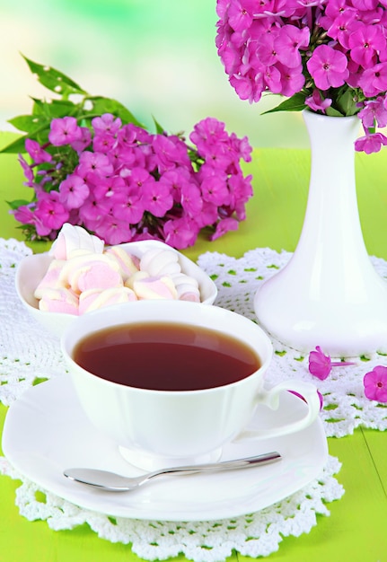 Schöner Strauß Phlox mit Tasse Tee auf dem Tisch auf hellem Hintergrund