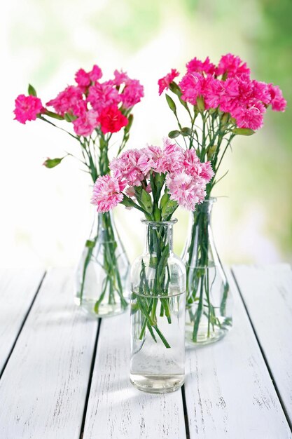 Schöner Strauß rosa Nelken in Vasen auf hellem Hintergrund