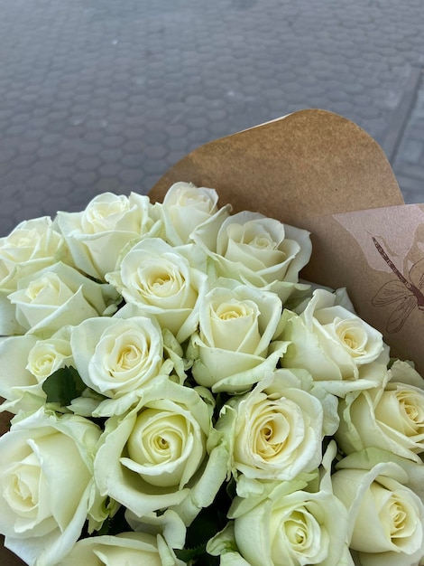 Schöner Strauß weißer Rosen mit Blättern auf grauem Hintergrund