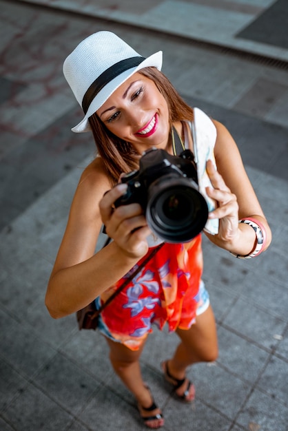 Schöner Tourist des jungen Mädchens, der Karte hält und mit Digitalkamera fotografiert.