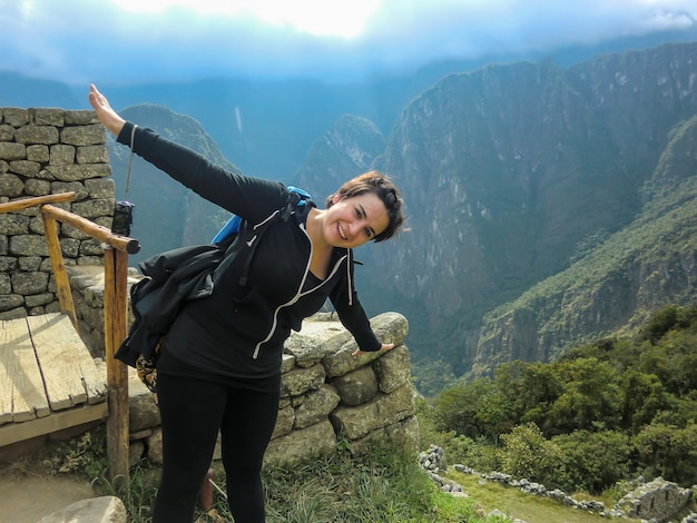 Schöner Tourist mit offenen Armen in den Ruinen von Machu Picchu, Cusco - Peru