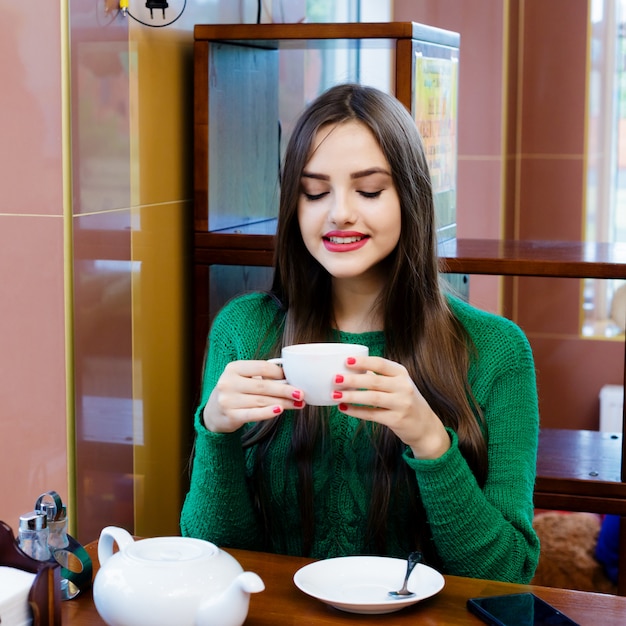 Schöner trinkender Tee der jungen Frau im Café