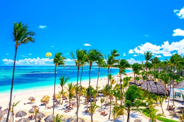 Schöner tropischer Atlantikstrand mit Palmen, Sonnenschirmen und Parasailing-Ballon. Luftaufnahme des tropischen Resorts Bavaro Strand Punta Cana in der Dominikanischen Republik.