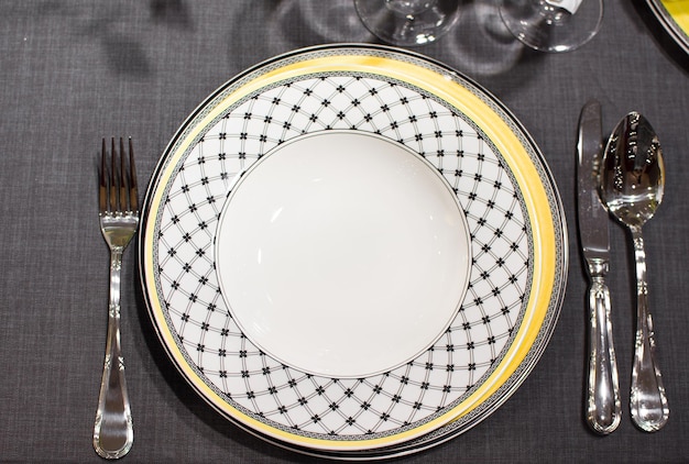 Schöner und eleganter weißer Teller mit gelbem und schwarzem einzigartigem geometrischem Muster an den Rändern