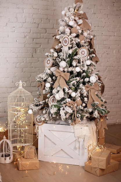 Schöner Weihnachtsbaum verziert mit Spielzeugbällen und Lichtergirlanden mit Geschenken aus Kraftpapier
