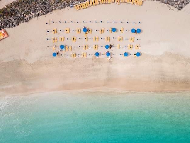 Schöner weißer Sandstrand mit Sonnenliegen und Sonnenschirmen aus der Luft