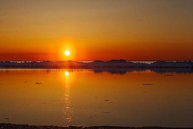 Schöner Wintersonnenuntergang am Meer mit Eisberg