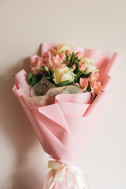 Schöner zarter rosa Blumenstrauß aus weißen Rosen und Eustoma in einer schönen Verpackung