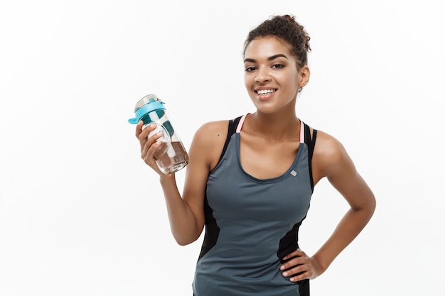 schönes Afroamerikanermädchen im Sport kleidet die Wasserflasche nach Training an.