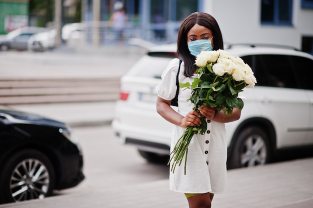 Schönes afroamerikanisches Mädchen in einem weißen Kleid mit Blumen in den Händen