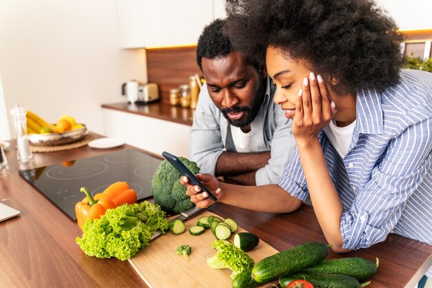 Schönes afroamerikanisches Paar, das zu Hause kocht Schönes schwarzes Paar, das das Abendessen zubereitet