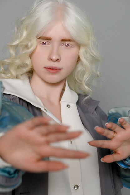 Schönes Albino-Mädchen mit weißer Haut, natürlichen Lippen und weißem lockigem Haar, das einen stylischen weißen Pullover trägt, Nahaufnahmefoto, Kopienraum, Schönheit, Mode. Blondes Mädchen