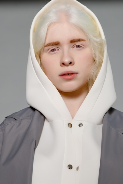 Schönes albino-mädchen mit weißer haut, natürlichen lippen und weißem lockigem haar, das einen stylischen weißen pullover trägt, nahaufnahmefoto, kopienraum, schönheit, mode. blondes mädchen