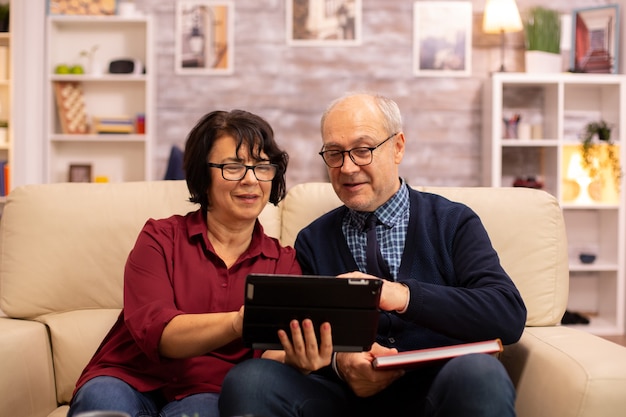 Schönes altes Paar, das ein digitales Tablet verwendet, um mit ihrer Familie zu chatten. Ältere Menschen mit moderner Technologie