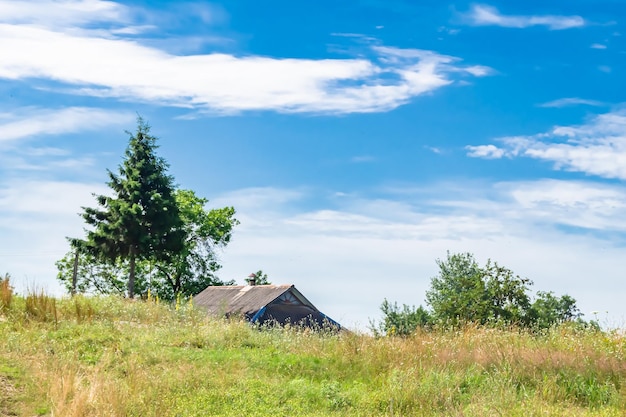 Schönes altes, verlassenes Bauernhaus auf dem Land vor natürlichem Hintergrund. Fotografie bestehend aus einem alten, verlassenen Bauernhaus am wilden Gras. Altes, verlassenes Bauernhaus über dem Himmel