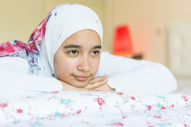 Schönes arabisches Mädchen auf Bett im modernen Schlafzimmer