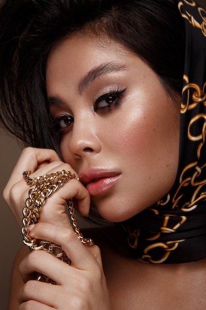 Schönes asiatisches brünettes Modell mit Volumenlocken, klassischem Make-up und sexy Lippen
