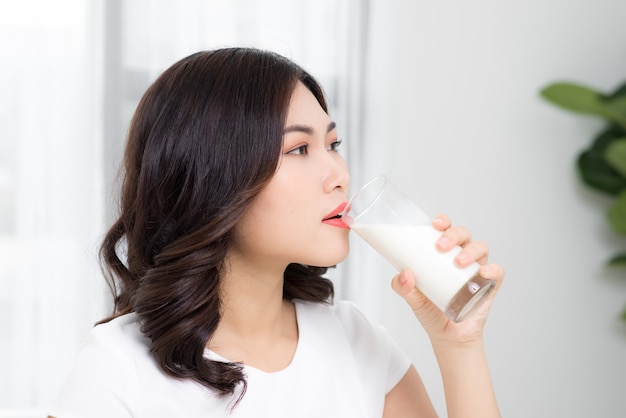 Schönes asiatisches Mädchen, das ein Glas Milch trinkt.