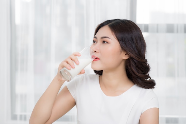 Schönes asiatisches Mädchen, das ein Glas Milch trinkt.