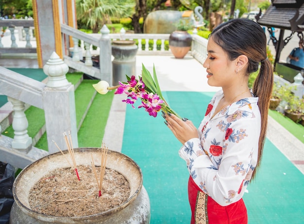 Schönes asiatisches Mädchen im großen buddhistischen Tempel in traditioneller Tracht