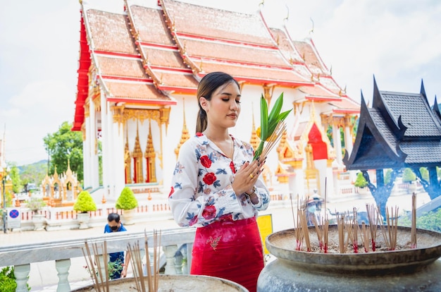 Schönes asiatisches Mädchen im großen buddhistischen Tempel in traditioneller Tracht