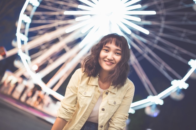 Schönes asiatisches Mädchen in einem Vergnügungspark in der Nacht, lächelnd