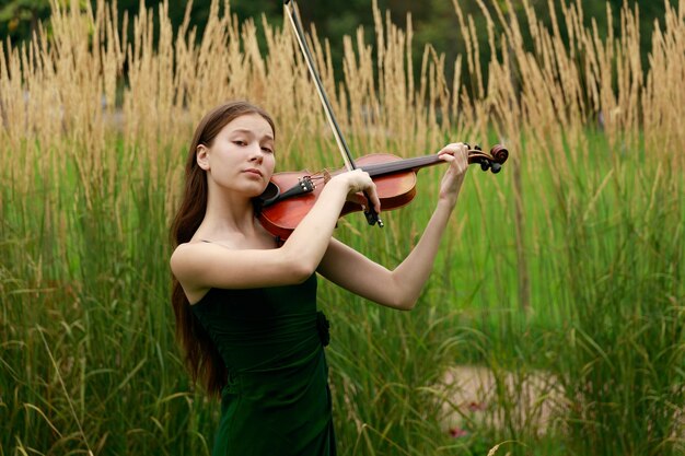 Schönes asiatisches Mädchen mit Geige in der Natur. Foto in hoher Qualität