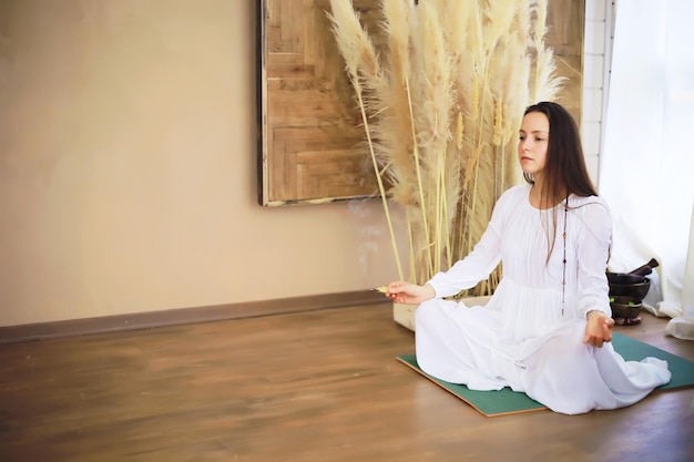 Schönes athletisches Mädchen, das Yoga-Übungen macht, genießt die Meditation zu Hause. Kein Stress, gesunde Gewohnheit, Angstabbaukonzept. Lotus-Pose