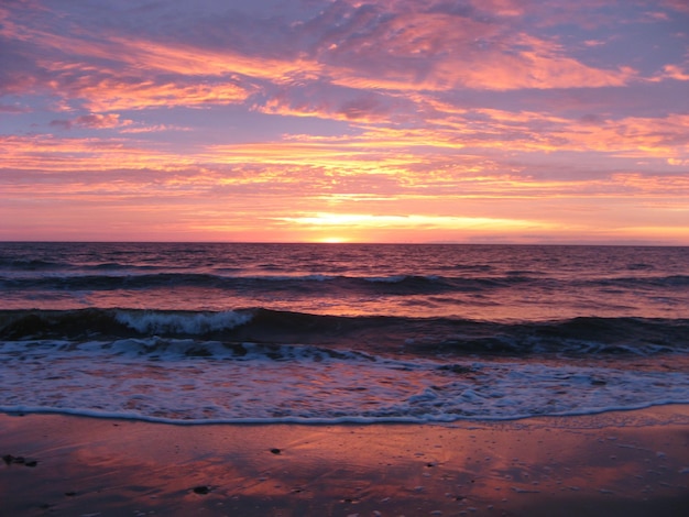 Schönes Aussehen des Meeres vor einem bewölkten orangefarbenen Himmel beim Sonnenuntergang