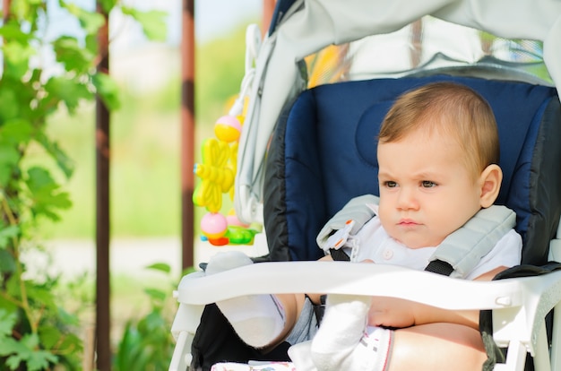 Schönes Baby, das in einem Kinderwagen draußen sitzt