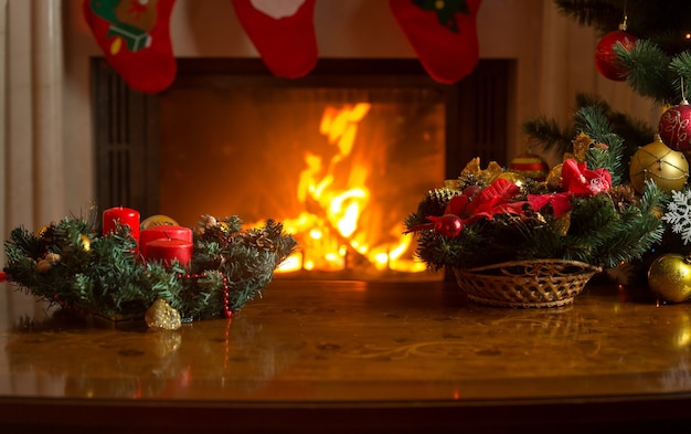 Schönes Bild des Tisches mit Weihnachtskranz vor brennendem Kamin und geschmücktem Weihnachtsbaum. Leerer Platz für Text.