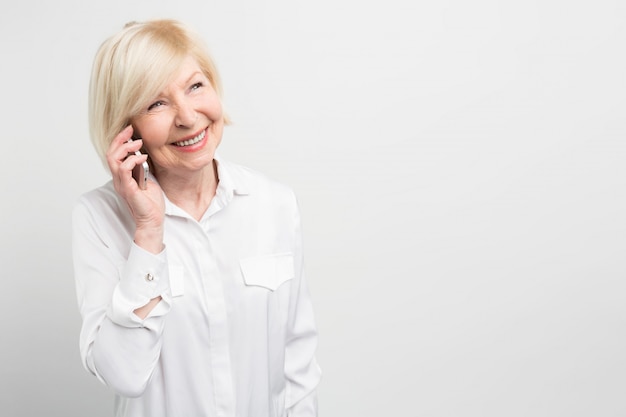 Schönes Bild von einer Dame, die seine Familie mit einem neuen Smartphone anruft. Sie liebt neue Technologien und versucht gerne, so viel wie möglich neue Geräte zu verwenden.