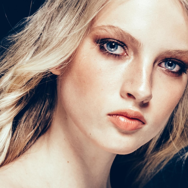 Schönes blondes Frauen-Schönheits-Modell Girl mit perfektem Make-up und Frisur über schwarzem Hintergrund.