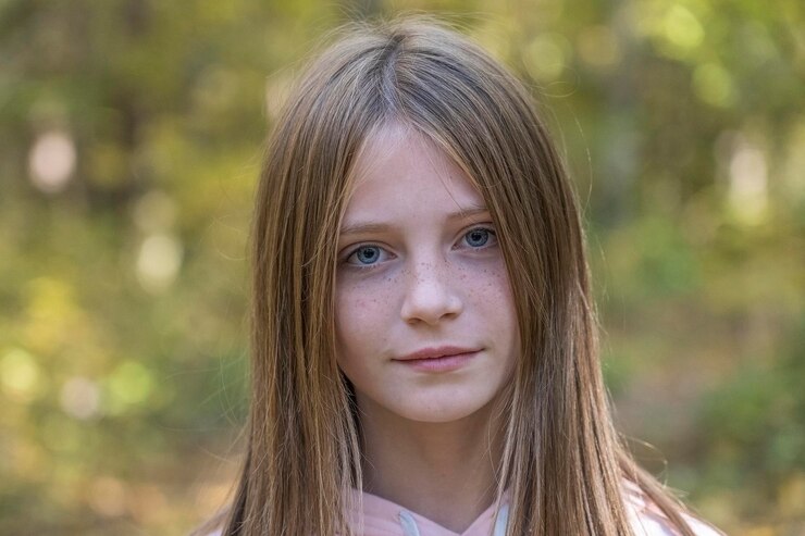 Schönes blondes junges Mädchen mit Sommersprossen im Freien auf Naturhintergrund im Herbst Nahaufnahme Porträt