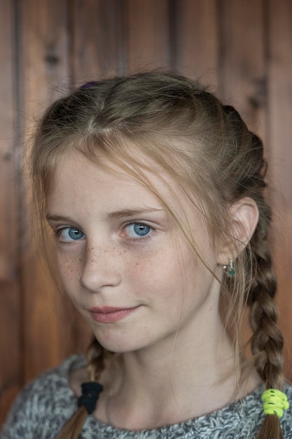 Schönes blondes junges Mädchen mit Sommersprossen zuhause auf hölzernem Hintergrundnahaufnahmeporträt