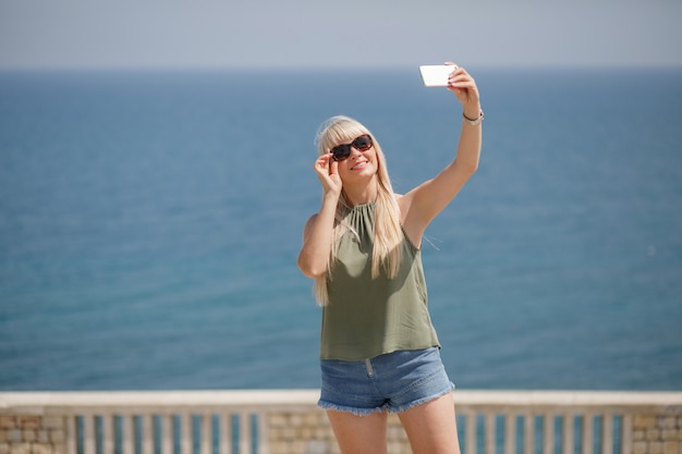 Schönes blondes Mädchen, das am Telefon spricht und Fotos in Ancona Italien macht. Europa Italien Reisen Sommer