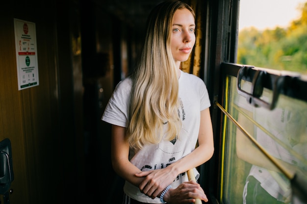 Schönes blondes Mädchen, das Fenster im Zug betrachtet