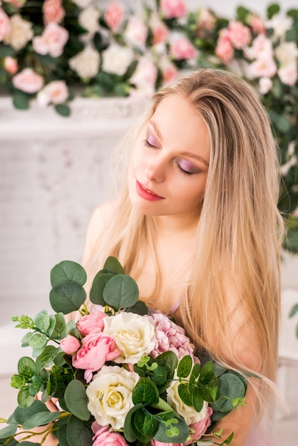 Schönes blondes Mädchen in einem langen weichen lila Kleid der Blumen, die aufwerfen. Konzept von Parfums, Mode und Schönheit