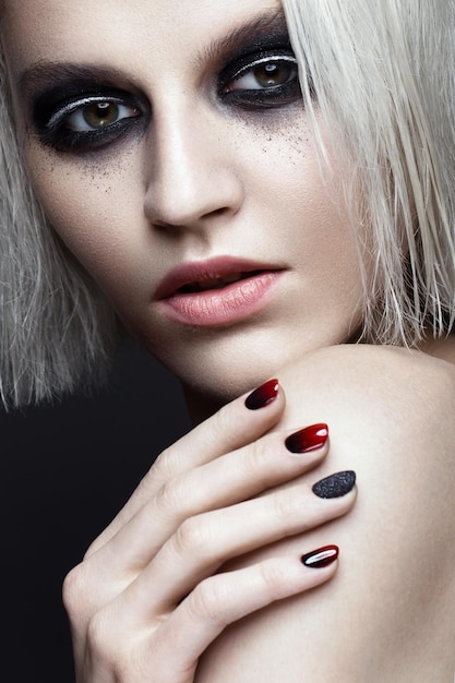 Schönes blondes Mädchen mit dunklen rauchigen Make-up- und Kunstmaniküre-Designnägeln. Schönheit Gesicht. Fotos im Studio geschossen