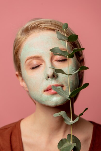 Schönes blondes Mädchen mit grüner Maske und Eukalyptuszweig