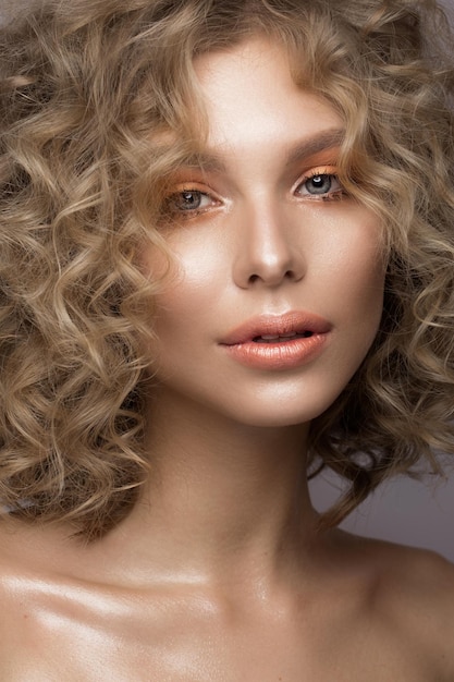 Schönes blondes Mädchen mit Locken und sanftem Make-up Schönheitsgesicht