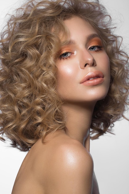 Schönes blondes Mädchen mit Locken und sanftem Make-up Schönheitsgesicht