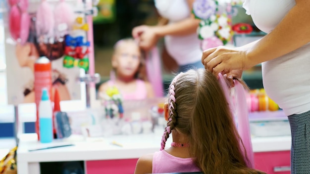 Foto schönes blondes mädchen von sieben jahren geflochten zwei schwanz macht eine frisur mit rosa locken von