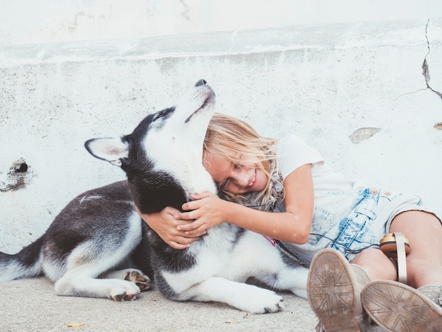 Schönes blondes Mädchen wirft mit Haustier Siberian Husky auf