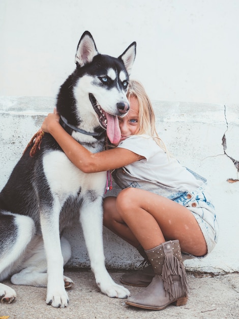 Schönes blondes Mädchen wirft mit Haustier Siberian Husky auf