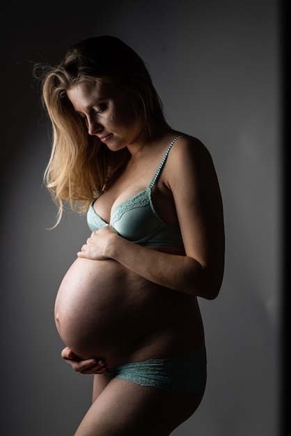 Schönes blondes Studioporträt der schwangeren Frau