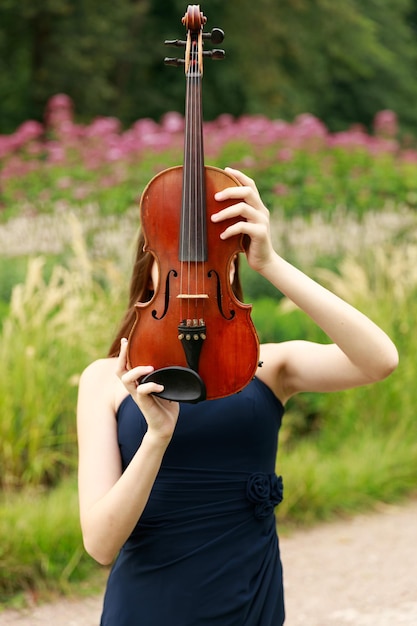 Schönes braunhaariges Mädchen asiatischen Aussehens mit einer Geige in der Natur. Musiker in der Natur. klassische Musik. Foto in hoher Qualität