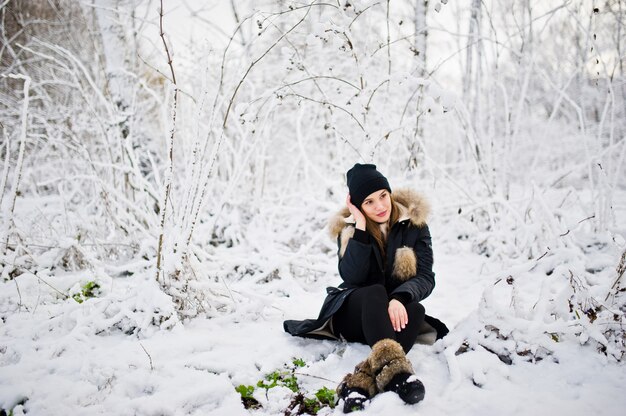 Schönes Brunettemädchen in der warmen Kleidung des Winters. Modell auf Winterjacke und schwarzem Hut.